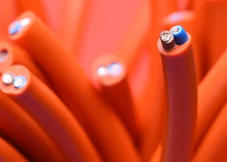 Close-up of thick orange electrical cables with cut ends, showing exposed copper and blue wires inside.