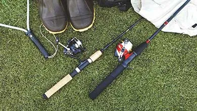 Fishing rods, reels, black rubber boots, and a backpack resting on grass.
