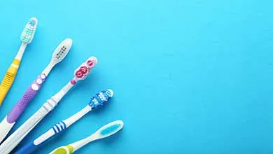 Colorful toothbrushes arranged on a bright blue background, highlighting molded plastic components.