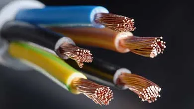 Close-up of several electrical wires with blue, brown, black, and yellow-green insulation, their ends stripped to reveal shiny, twisted copper strands against a dark background.